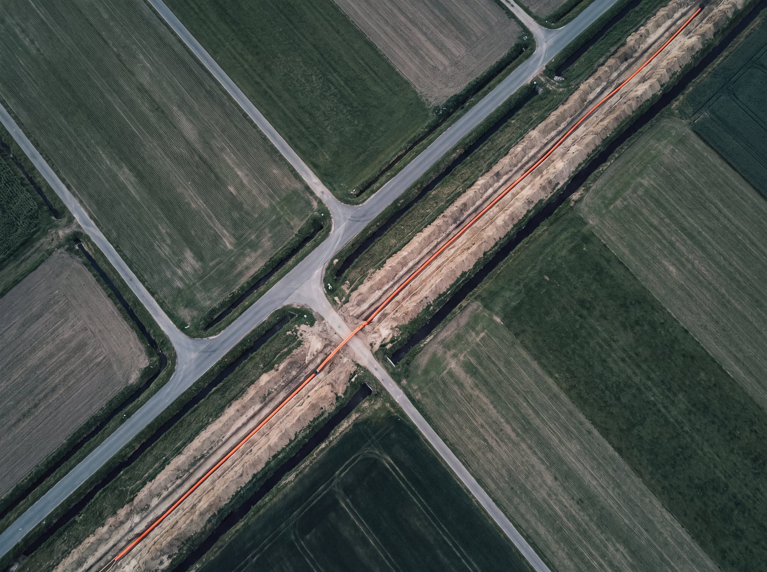 Luftaufnahme einer Bahntrasse zwischen Feldern mit kreuzenden Wirtschaftswegen